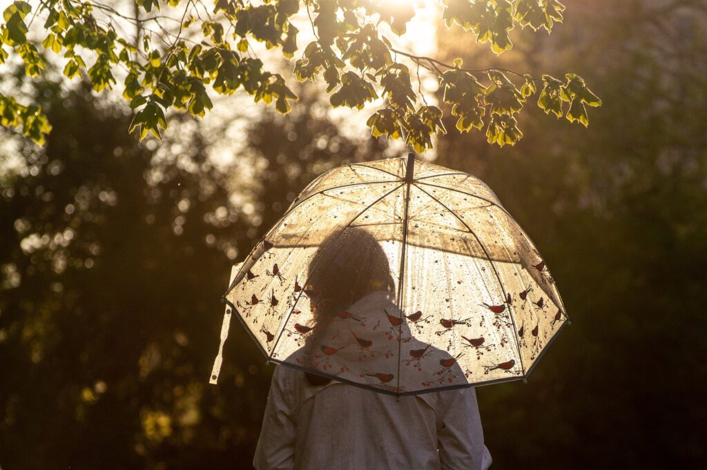 a woman walking during a light rain with an umbrella