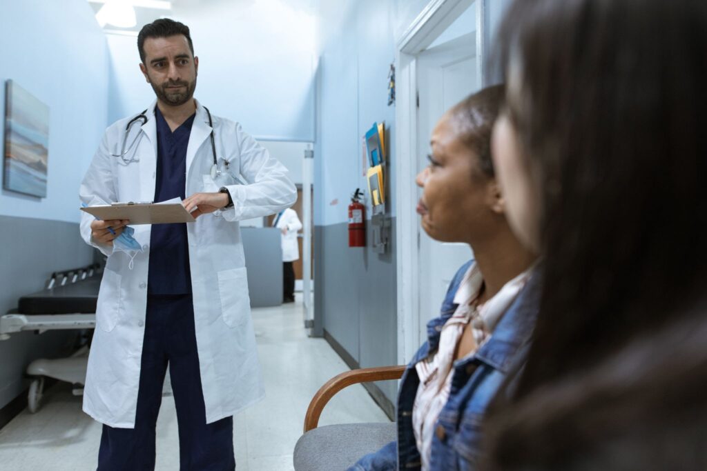 a doctor greeting two individuals in a hallway at a hospital

