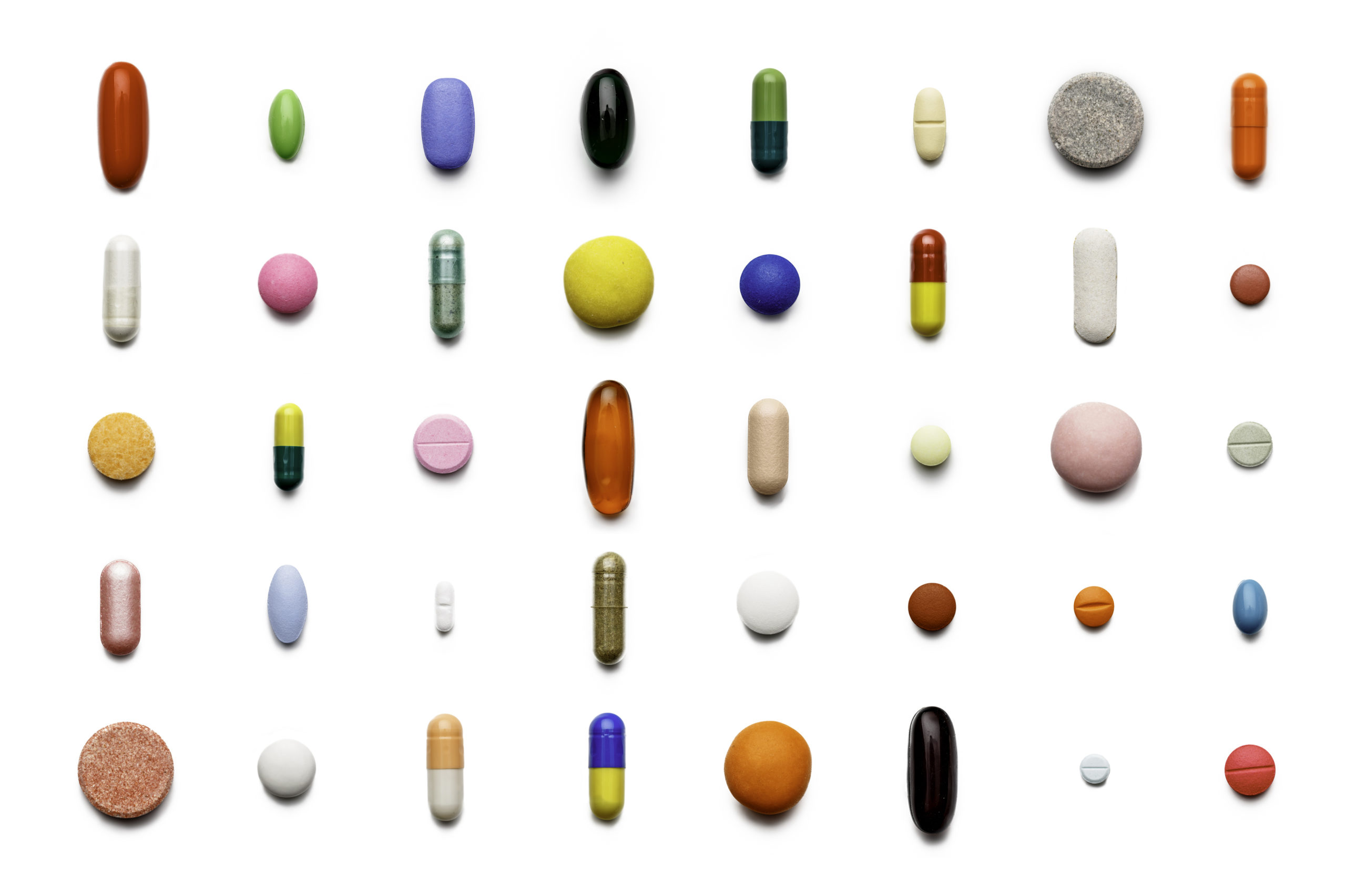 Array of large group of assorted capsules and pills on white background. High resolution image.