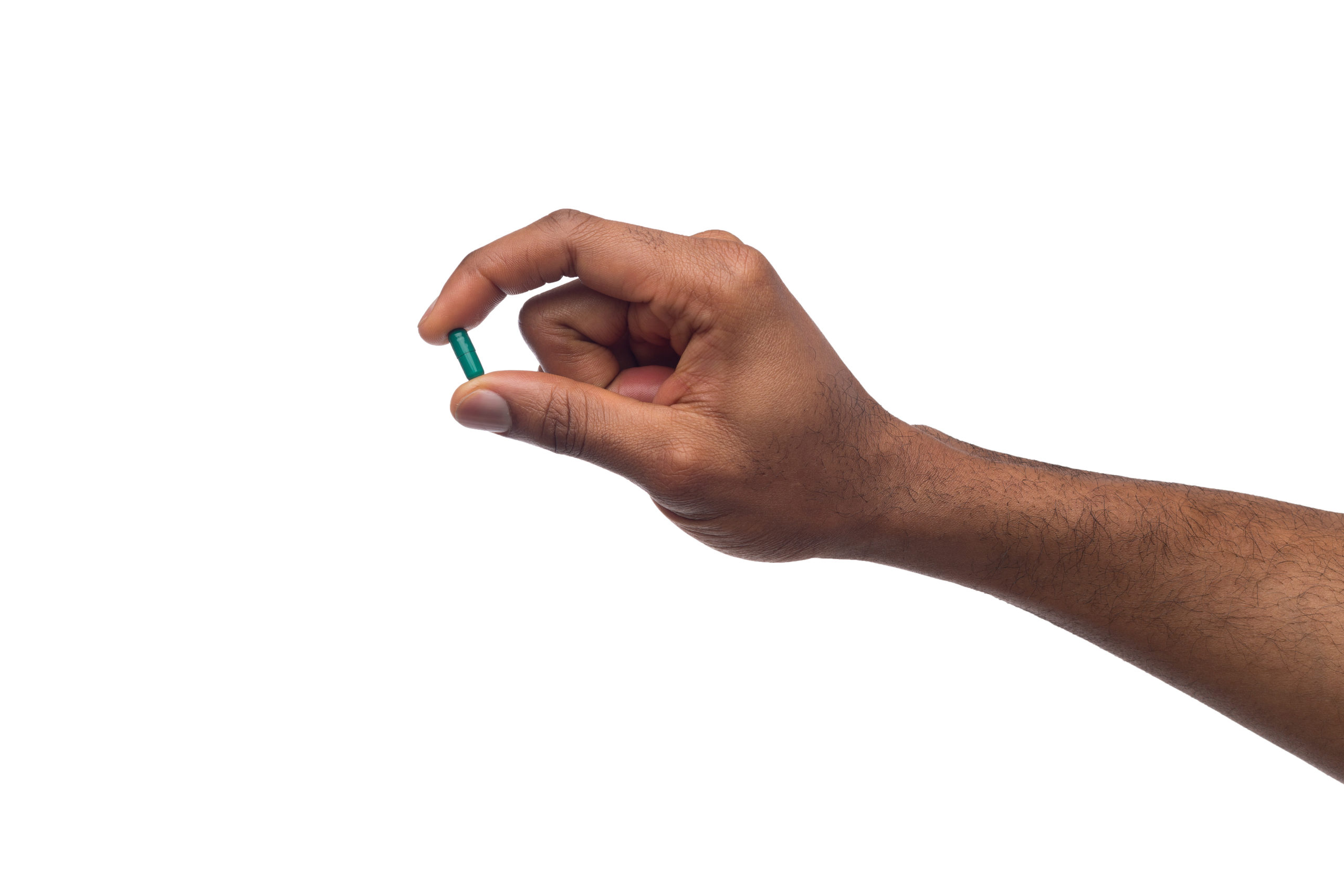 Black hand holding a pill isolated on white background