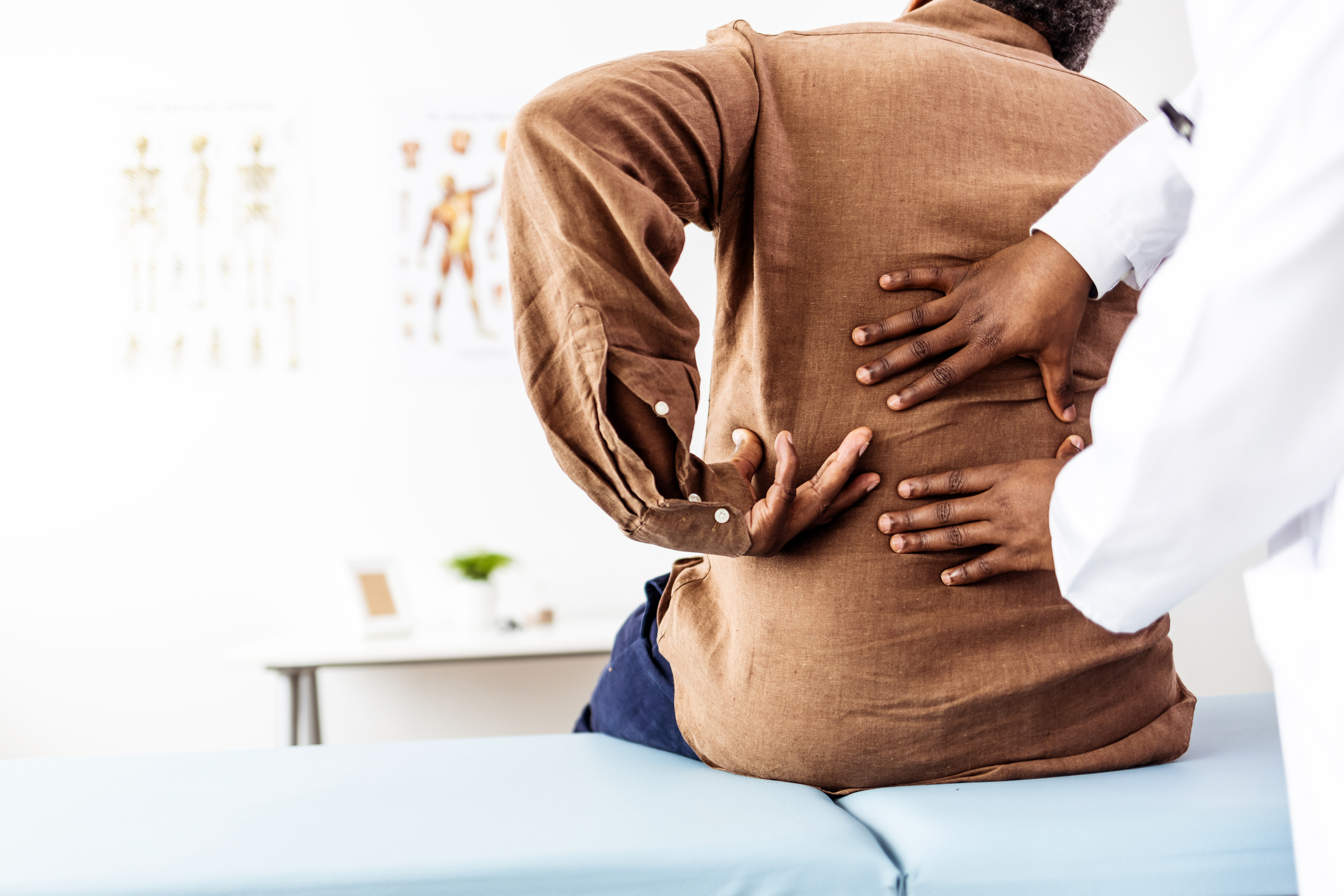 Doctor physiotherapist doing healing treatment on man’s back